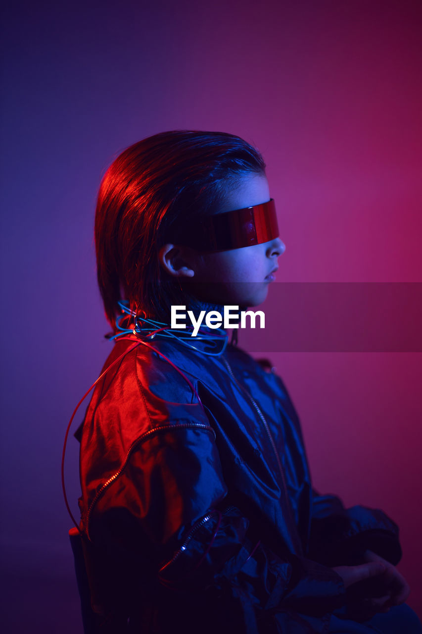 Portrait cyberpunk boy child in vr glasses in blue and red tones. game, virtual reality