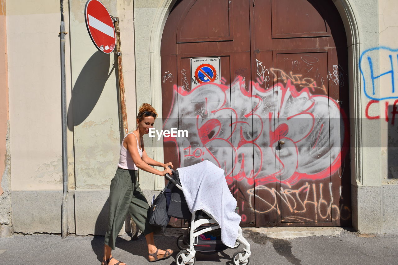 FULL LENGTH OF YOUNG MAN SITTING ON GRAFFITI