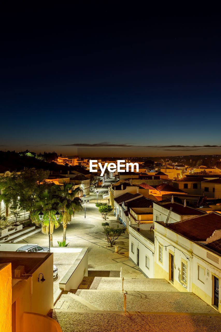 HIGH ANGLE VIEW OF ILLUMINATED BUILDINGS IN CITY AGAINST CLEAR SKY