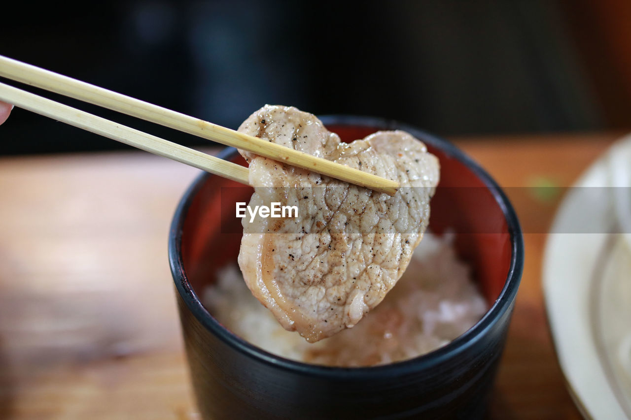 Close-up of chopsticks holding meat