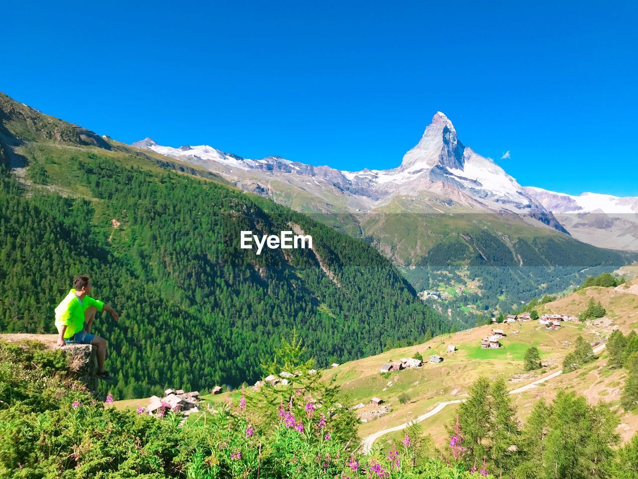 Man sitting on mountain against sky