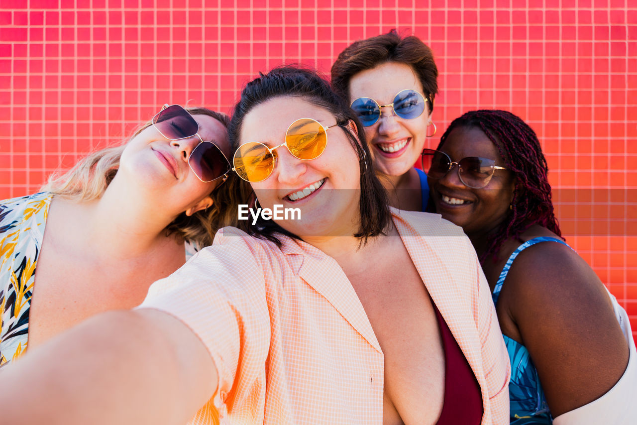 portrait of smiling friends standing against sky