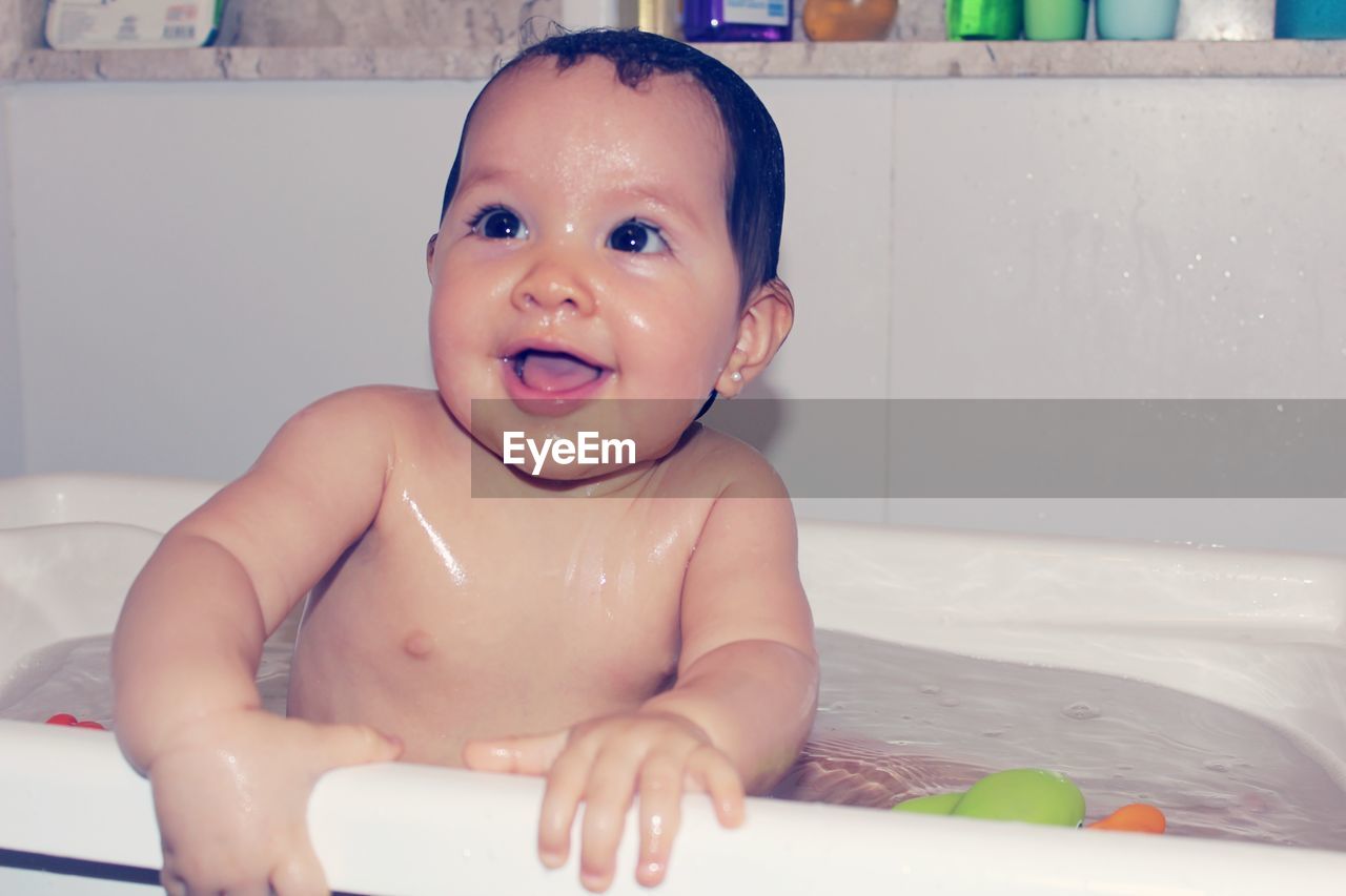 Thoughtful cute naked baby girl in bathtub