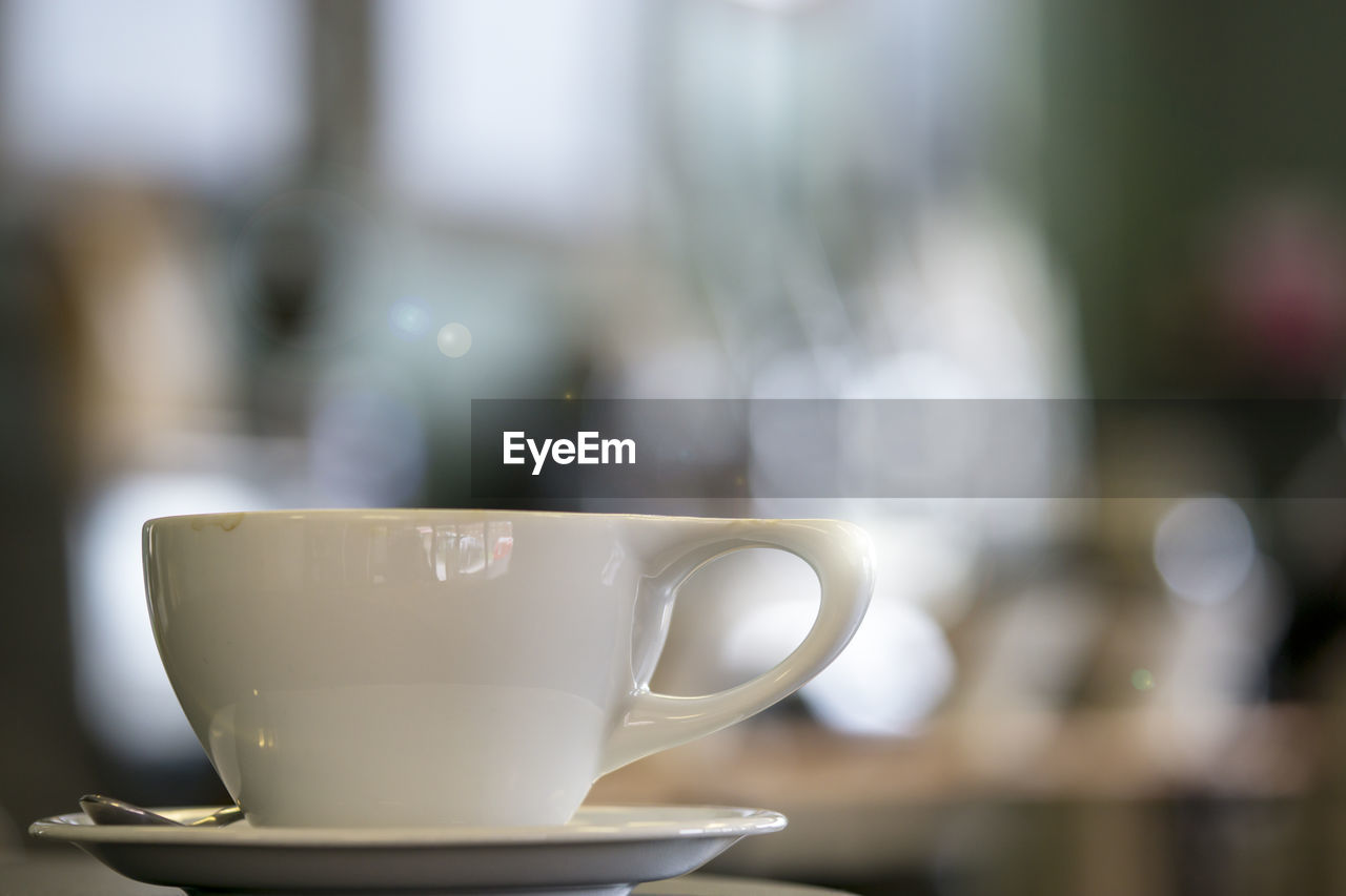 CLOSE-UP OF COFFEE CUP WITH SPOON ON TABLE