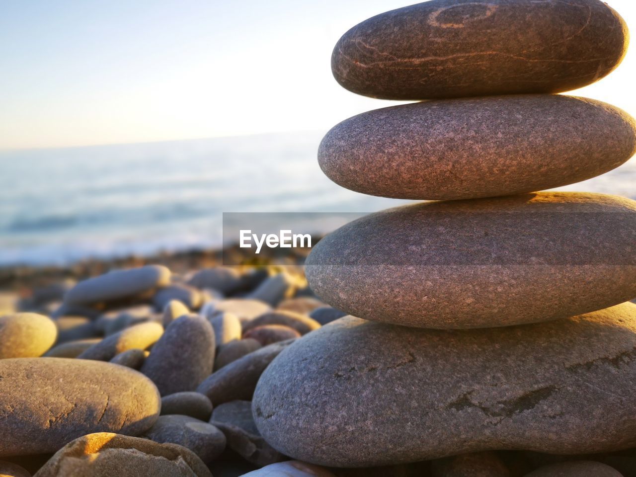 Close-up of stones stacked at beach against sky