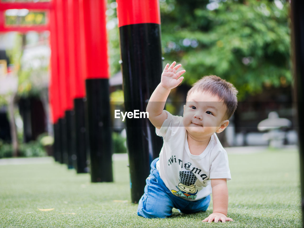 Baby boy playing on grass amidst torii gates at park