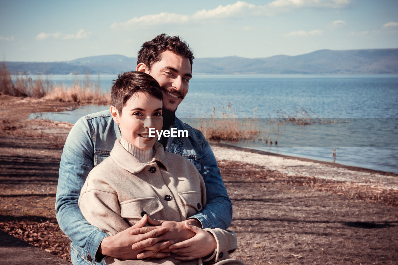 Beautiful couple sitting on the shore of lake bracciano in italy.