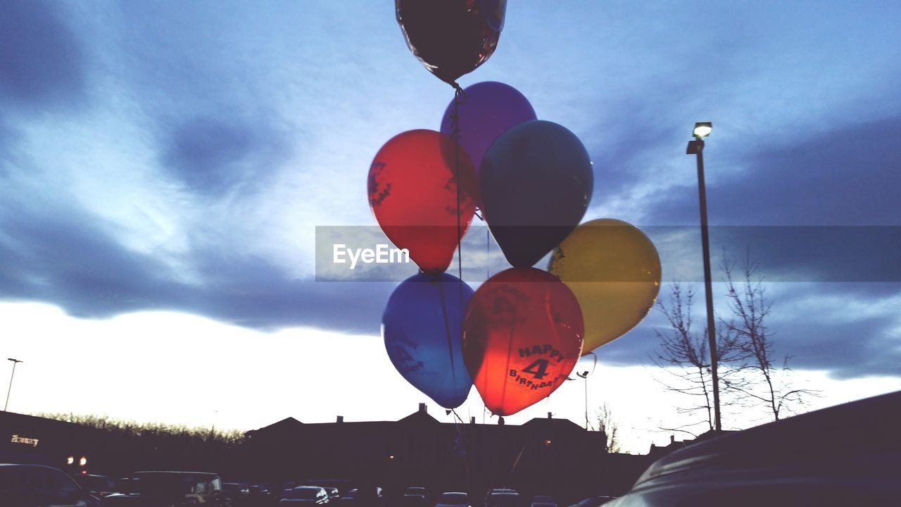 Low angle view of colorful balloons flying against cloudy sky