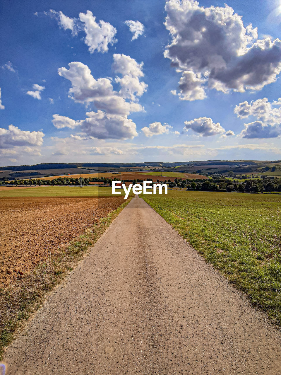 Road amidst field against sky