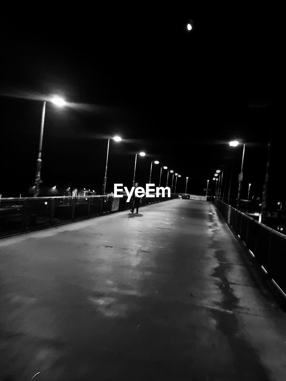 EMPTY ROAD ALONG STREET LIGHTS AT NIGHT