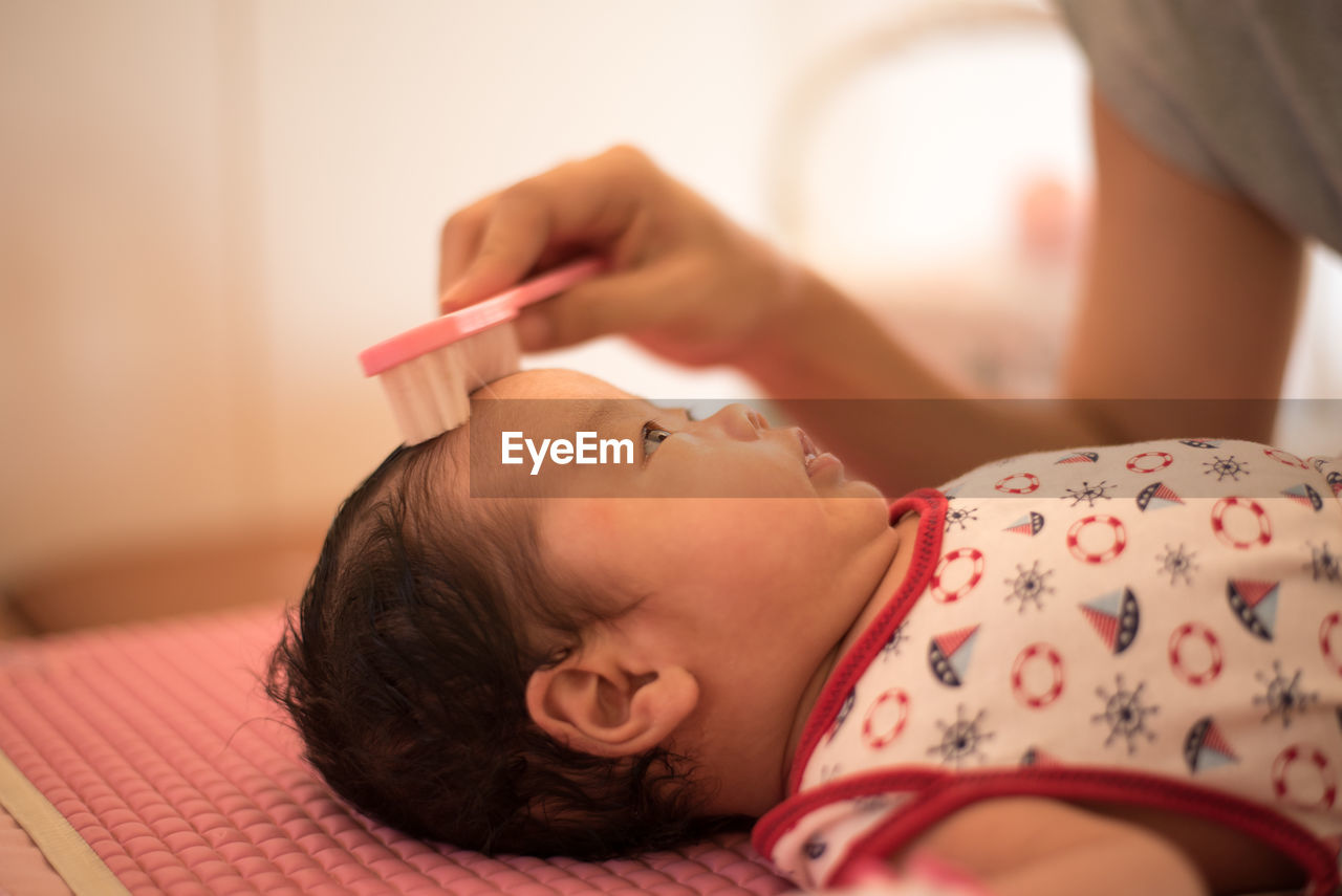 Close-up of baby girl on bed at home