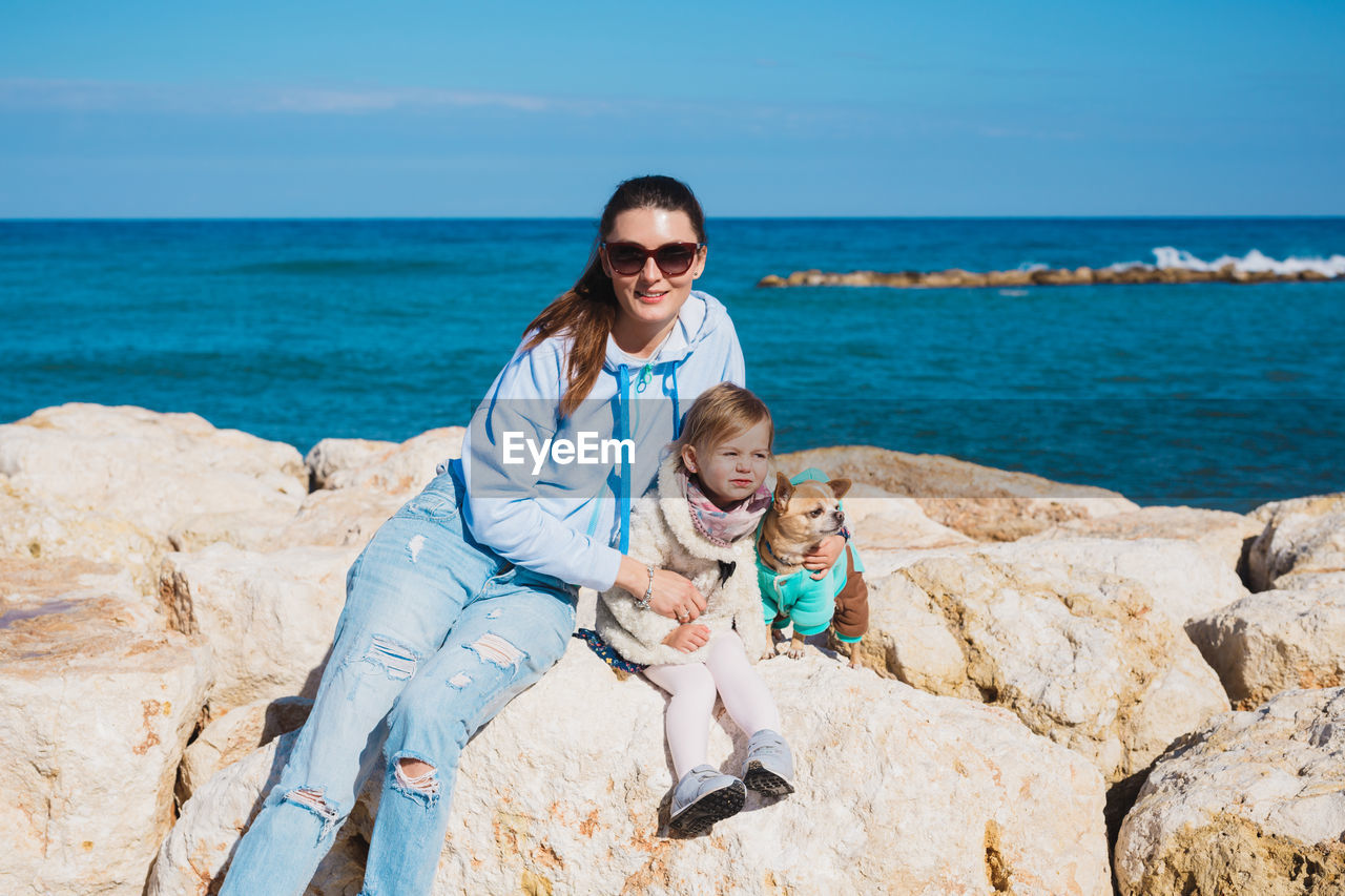 portrait of woman sitting on rock at beach