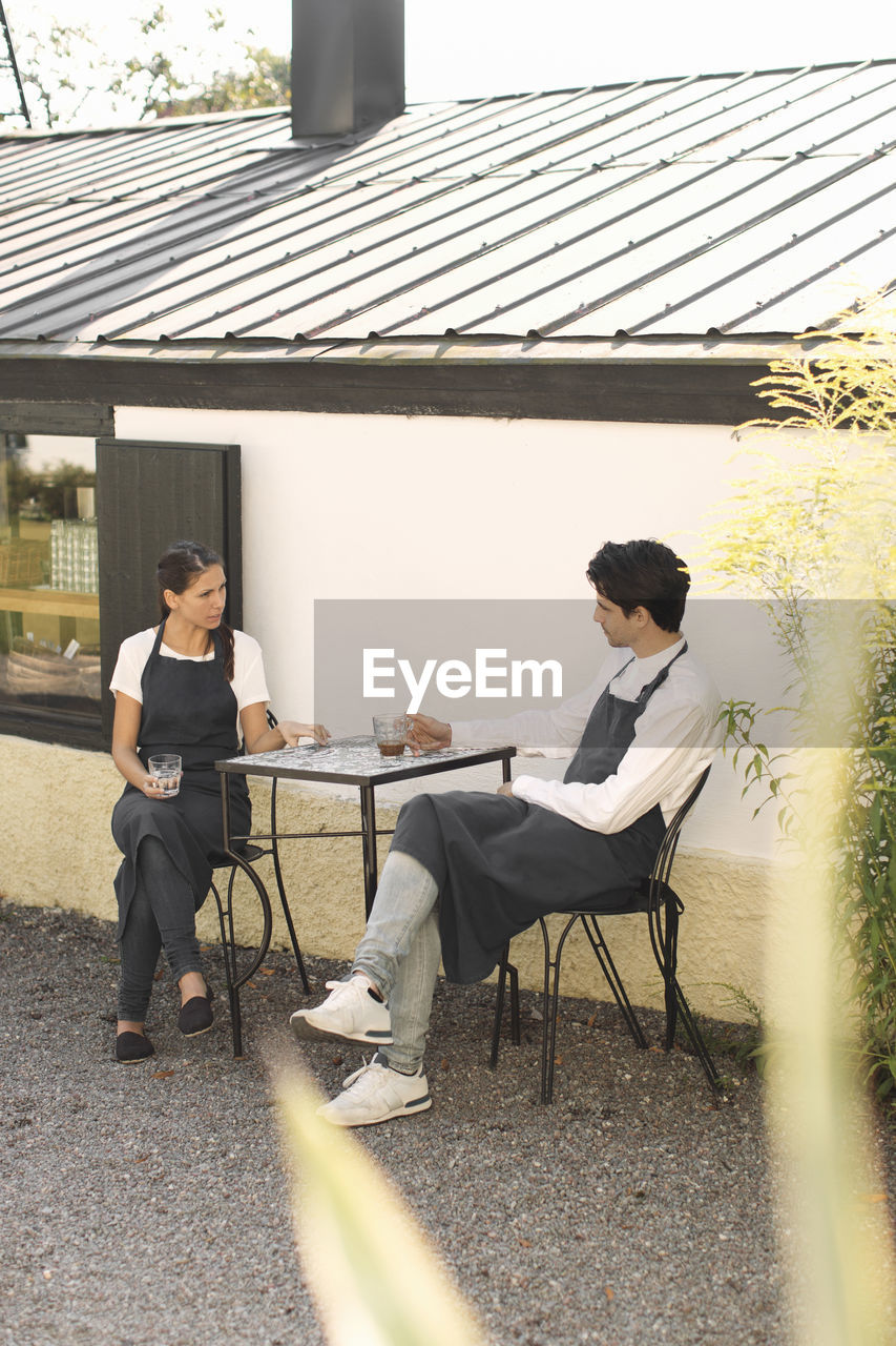 Waitress and waiter taking coffee break outside restaurant