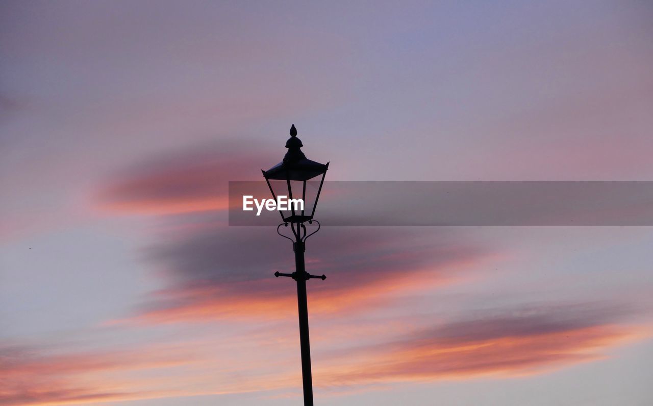 LOW ANGLE VIEW OF ILLUMINATED STREET LIGHT AGAINST SKY DURING SUNSET