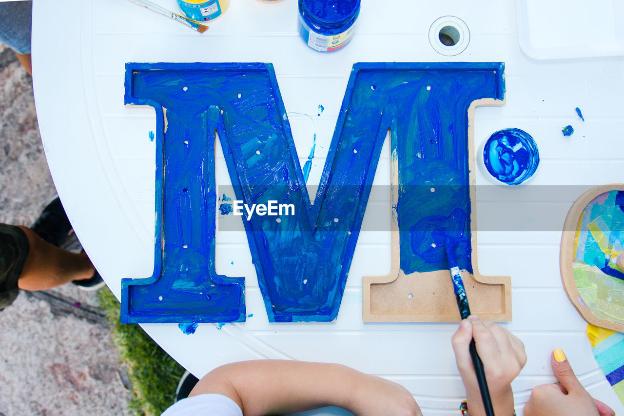 High angle view of kid painting wooden letters. diy hand craft. water colour painting. 