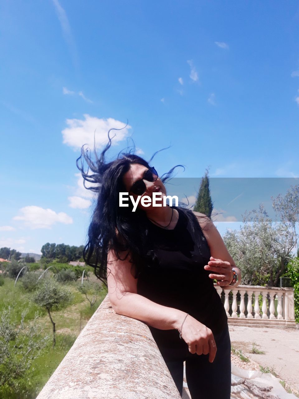 BEAUTIFUL YOUNG WOMAN LOOKING DOWN AGAINST SKY