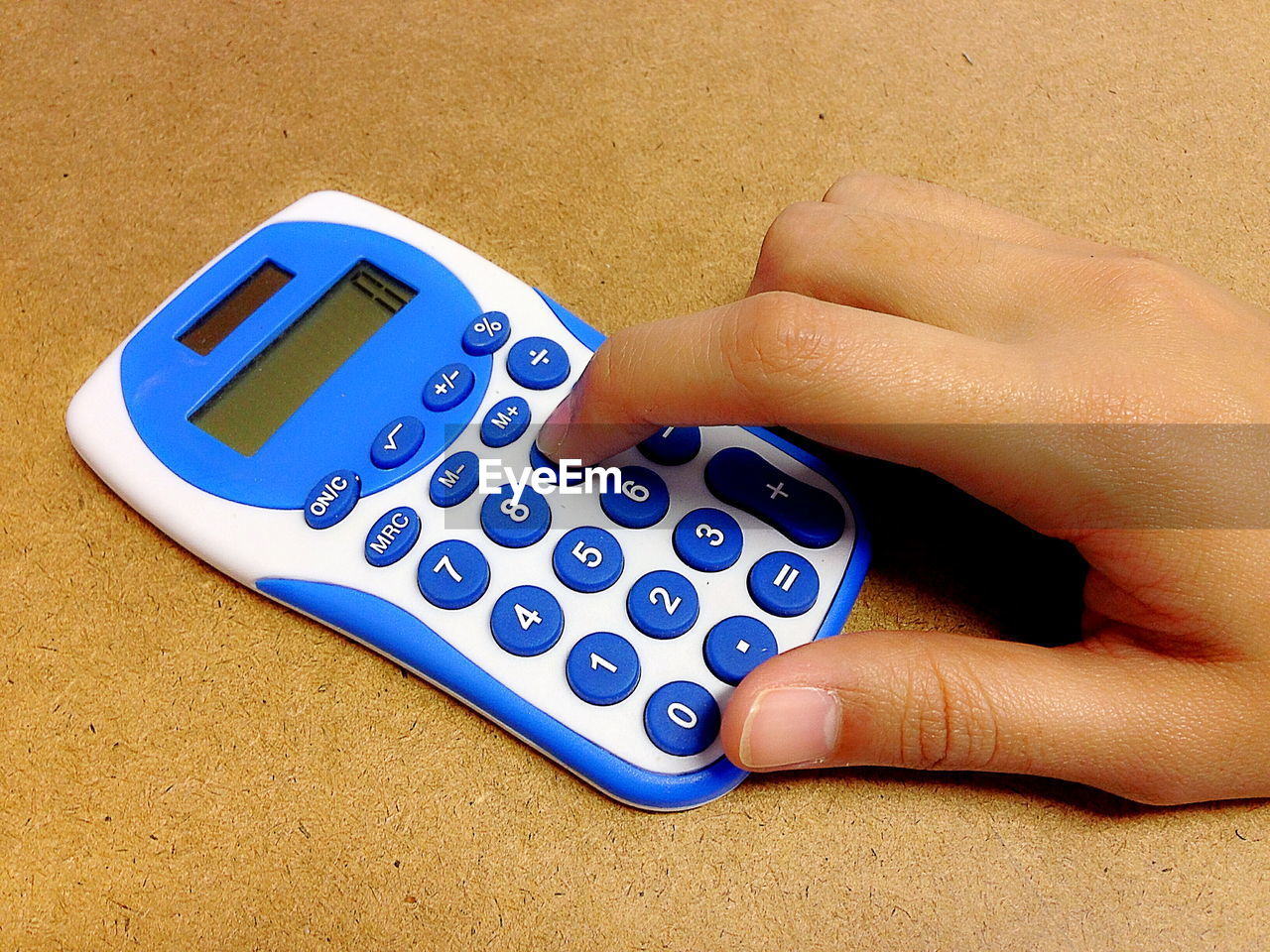 Cropped image of hand using calculator on table