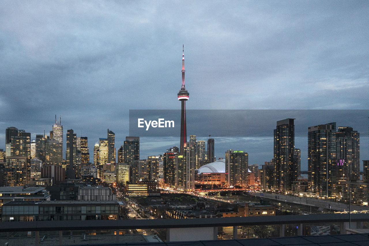 Illuminated buildings in toronto city against cloudy sky