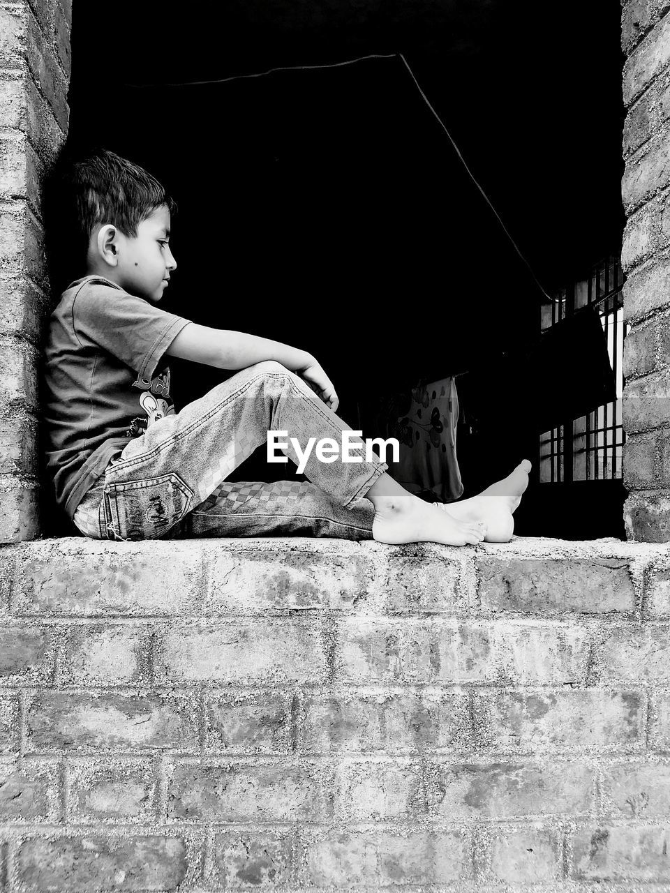 Boy sitting on retaining wall