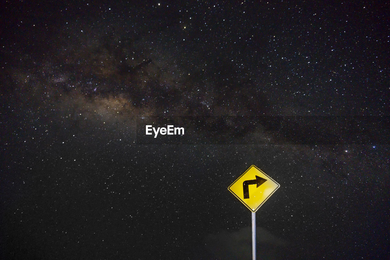 Road sign against sky at night