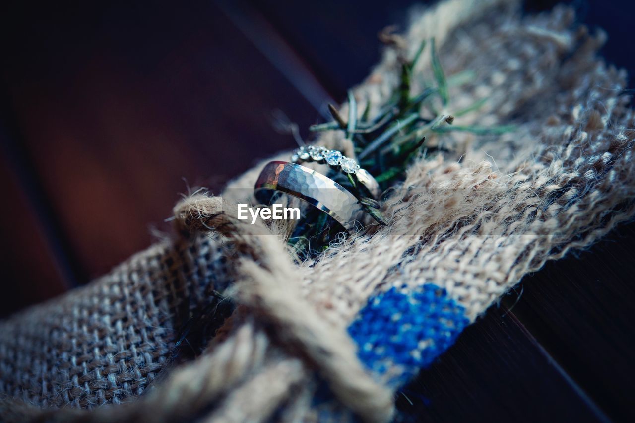 Close-up of wedding rings with rosemary on burlap