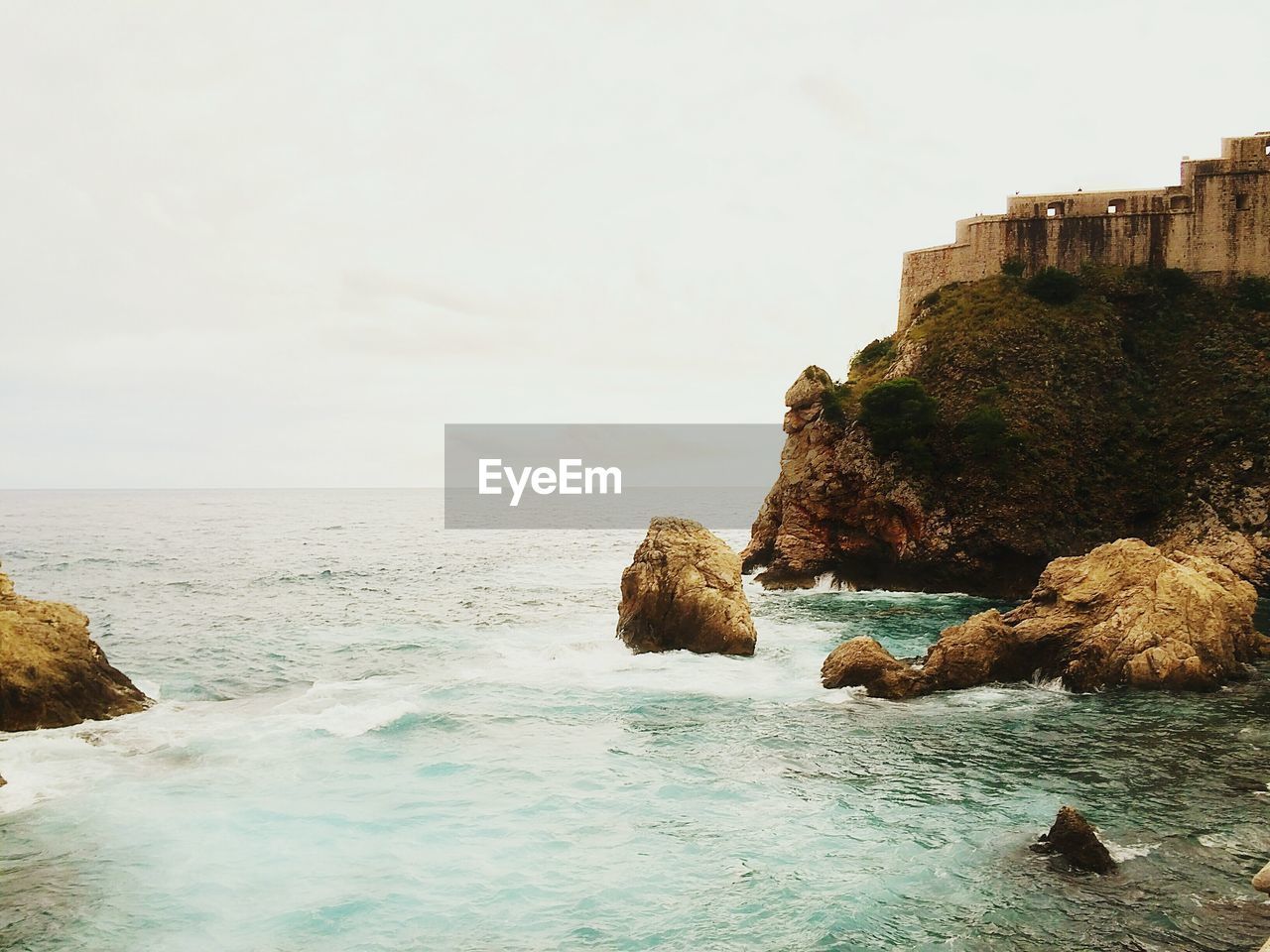 Fort on cliff by sea against sky