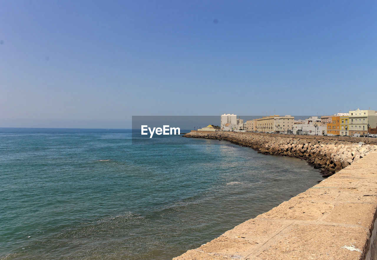 Scenic view of sea in front of city against sky