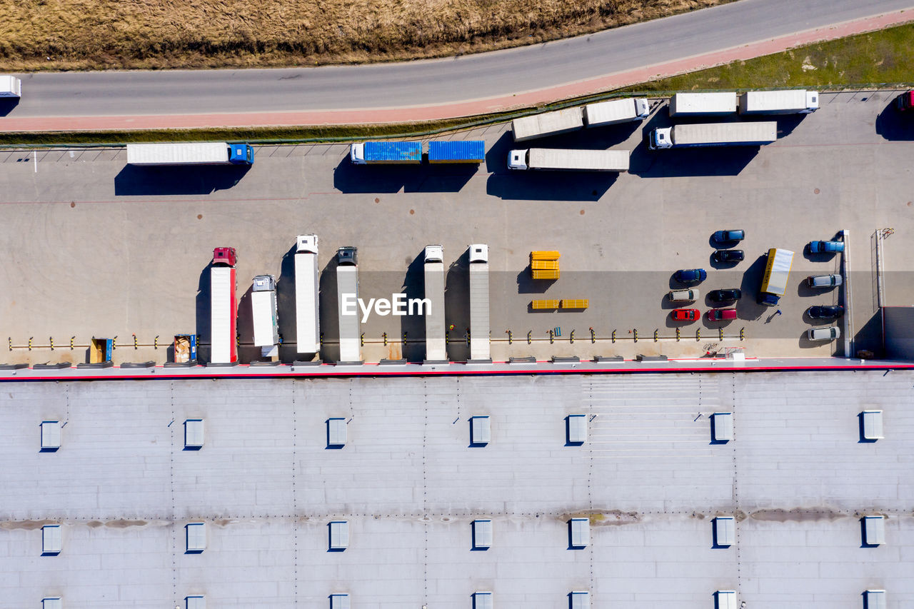 Aerial shot of truck with attached semi trailer leaving industrial warehouse/ storage building