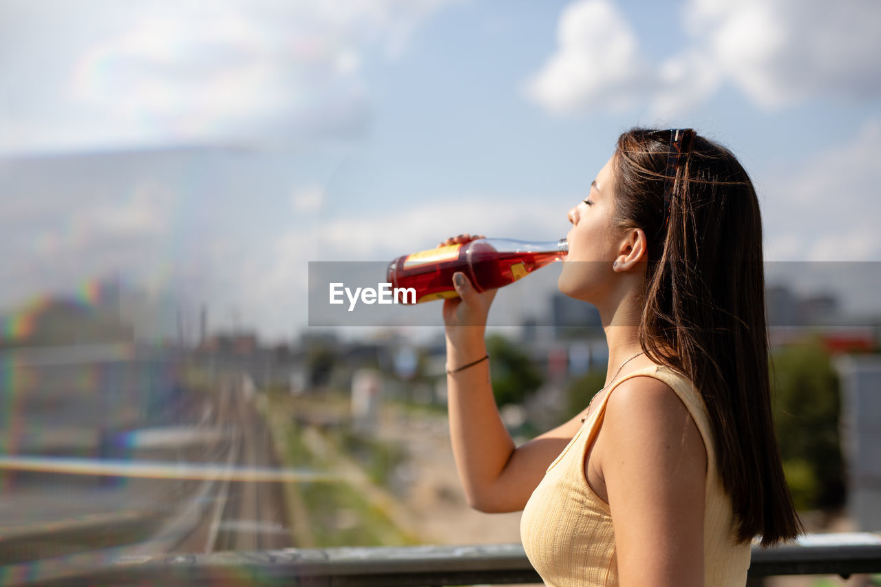 Woman drinking while standing in city