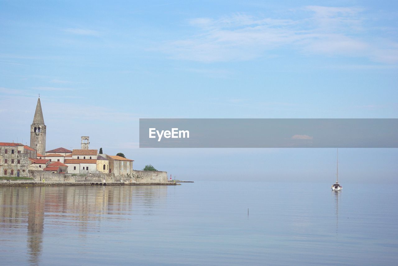 Buildings by sea against sky