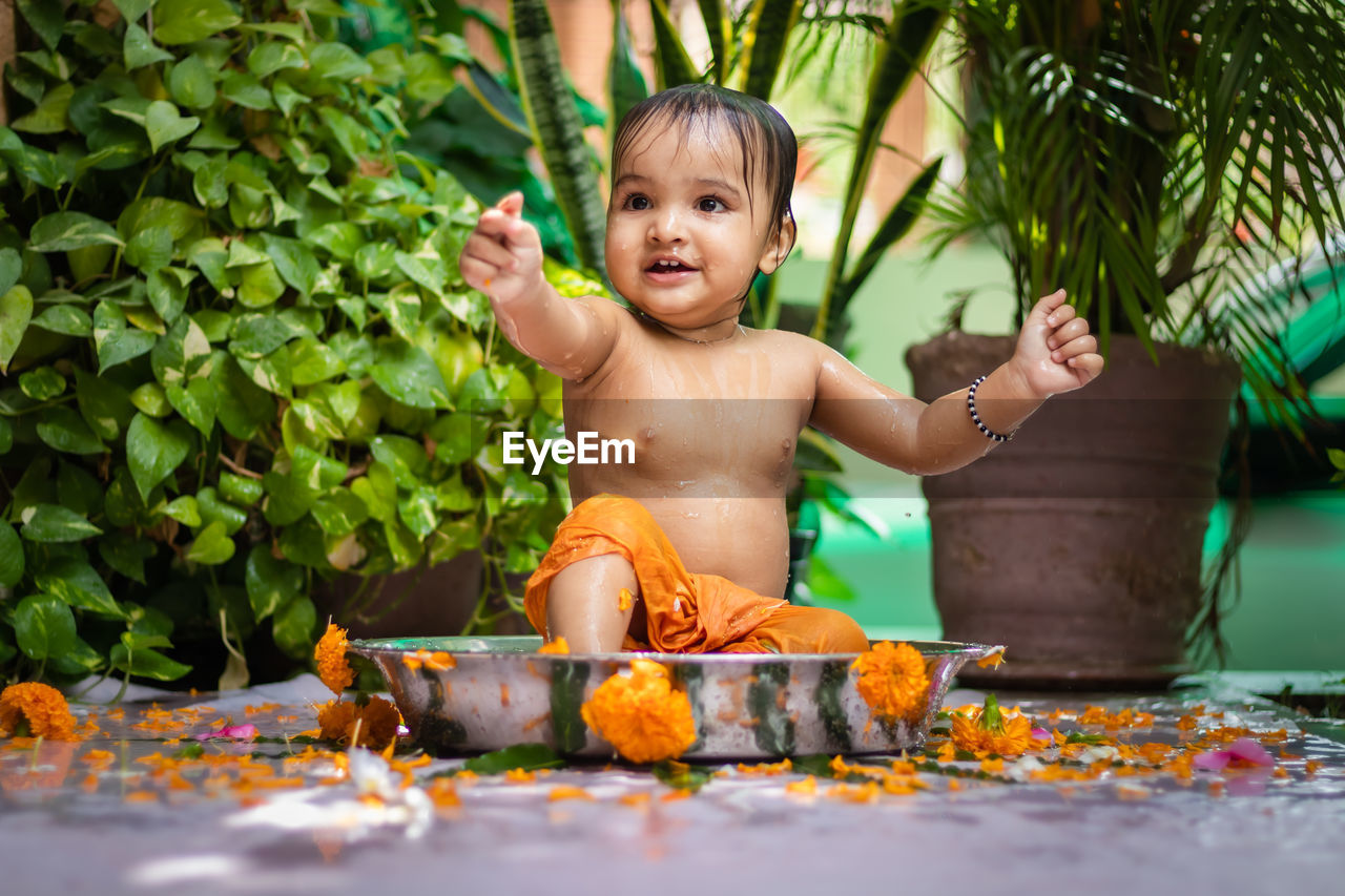 Cute toddler baby boy bathing in decorated bathtub at outdoor from unique perspective