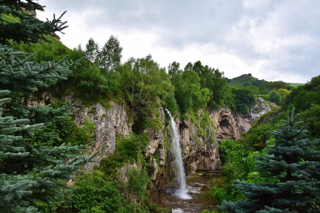 Scenic view of waterfall in forest against sky