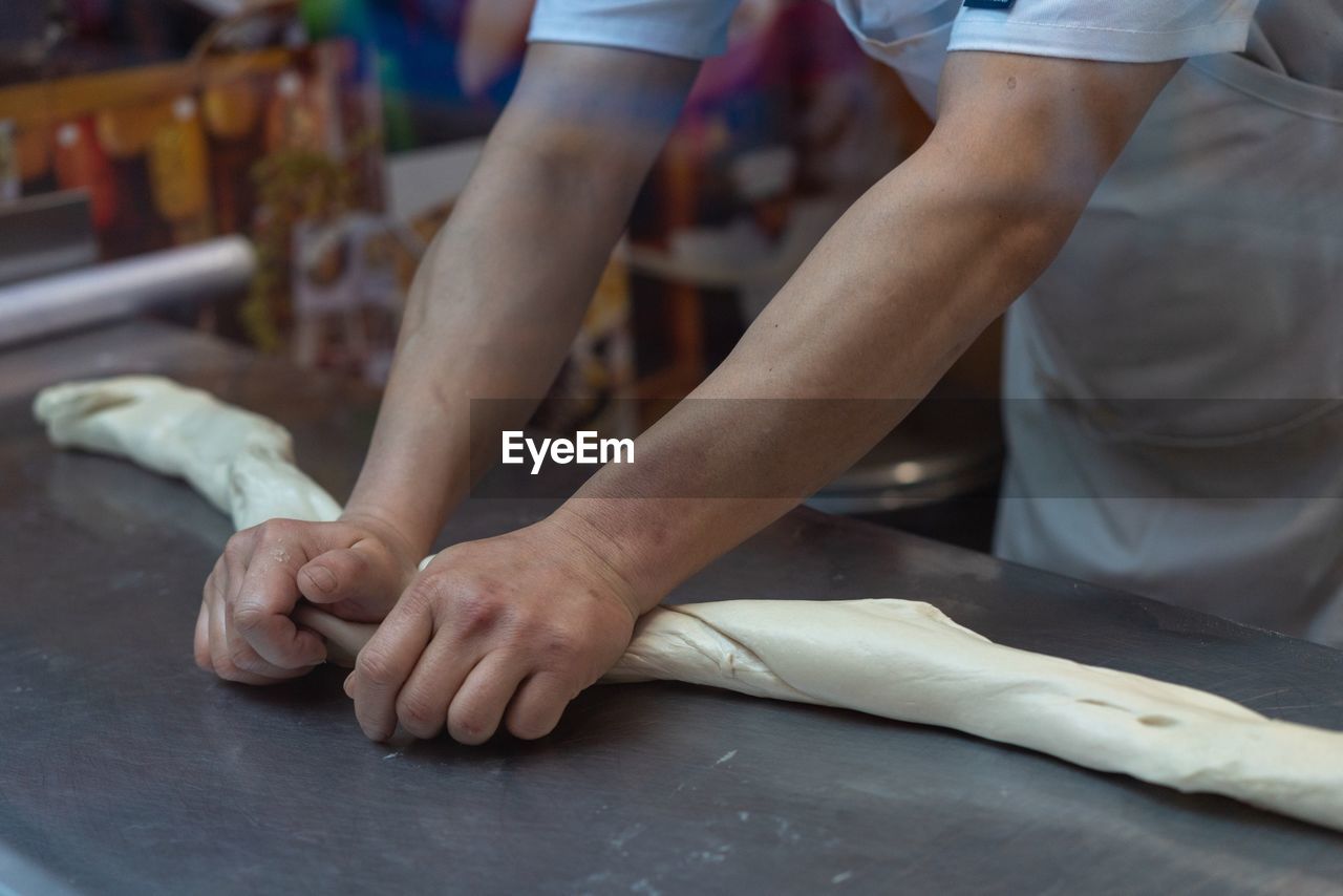 Midsection of chef kneading dough in kitchen