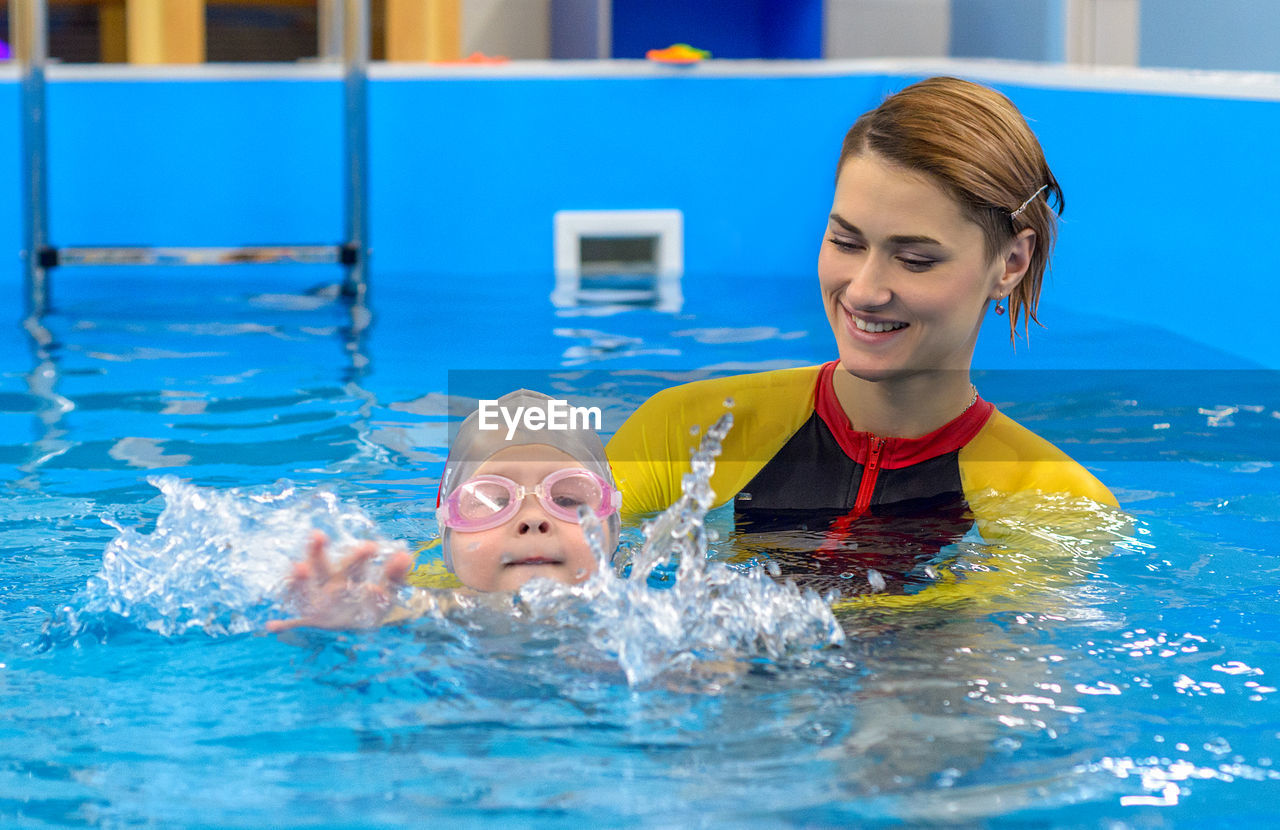 The coach teaches the child to swim in the pool