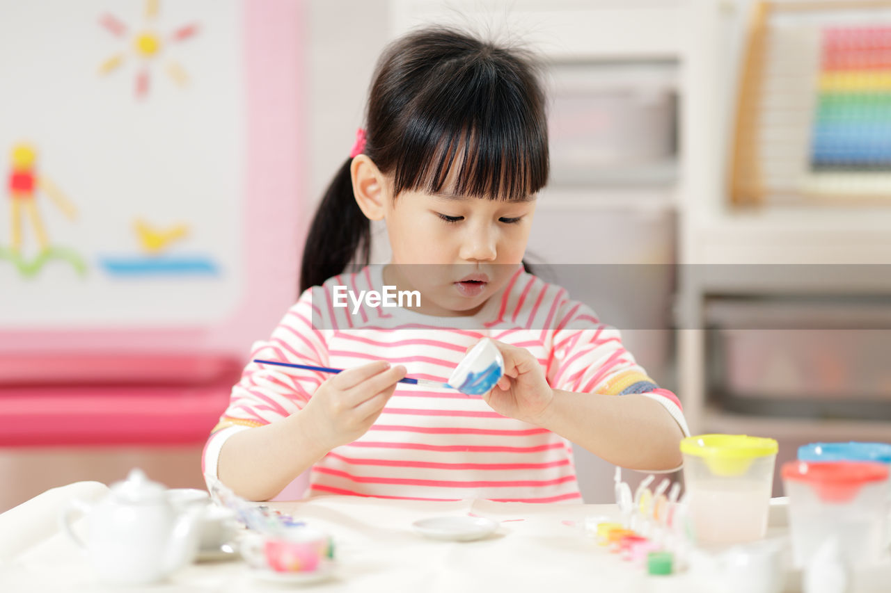 Young girl decorating handmade craft for home schooling