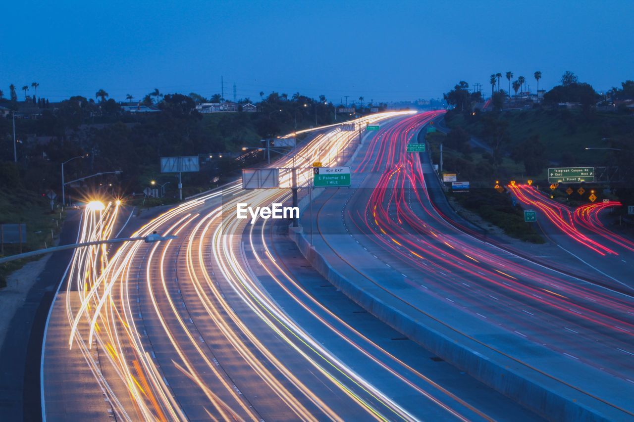 light trail, long exposure, illuminated, night, motion, transportation, road, city, speed, architecture, traffic, street, tail light, highway, blurred motion, sky, built structure, dusk, building exterior, no people, nature, mode of transportation, high angle view, city life, city street, street light, motor vehicle, evening, cityscape, outdoors, headlight, twilight, lighting equipment, car, light - natural phenomenon, curve, landscape, travel destinations, infrastructure, travel, lane, on the move, blue, building