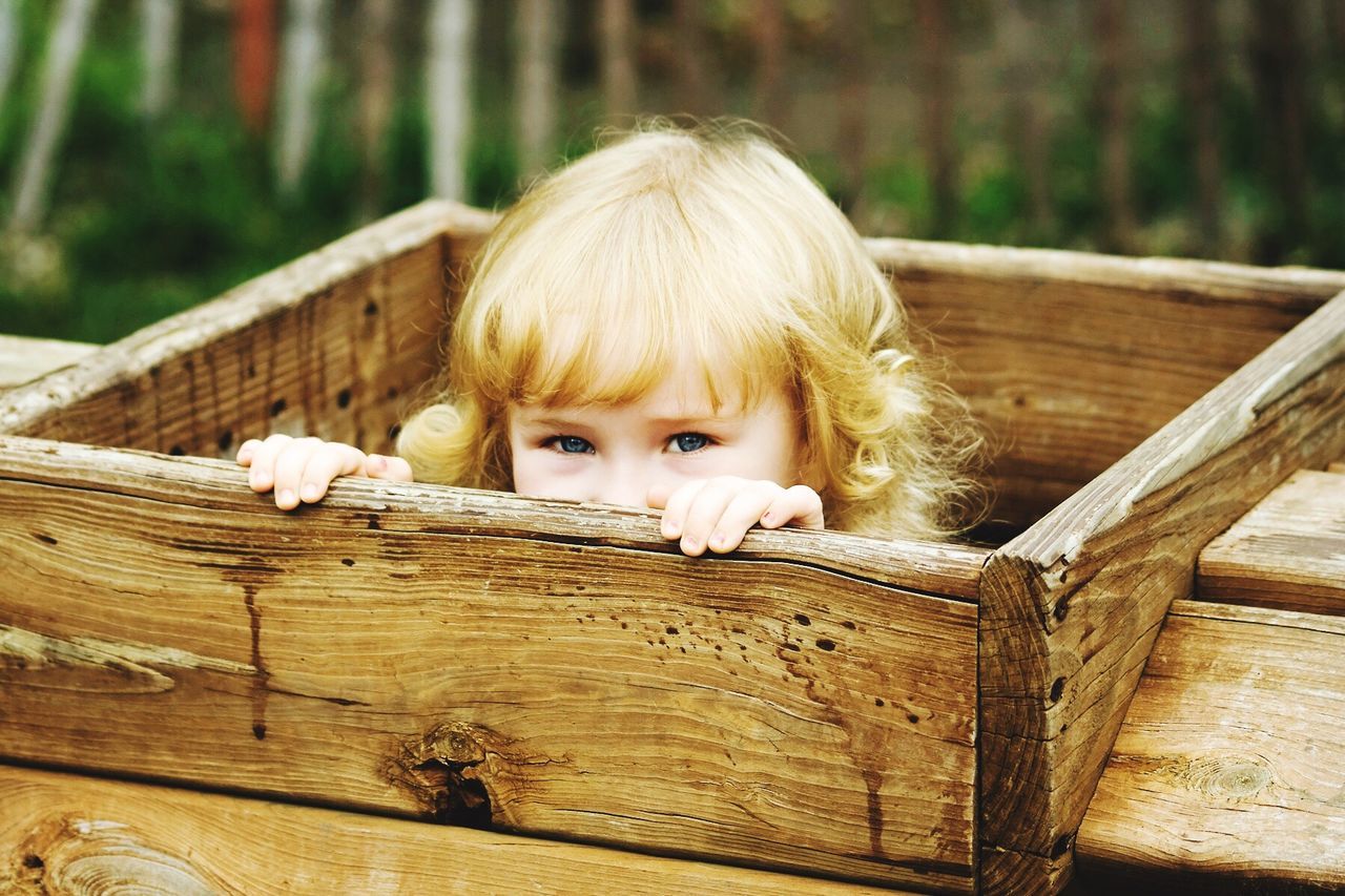 Portrait of cute girl hiding in wooden box