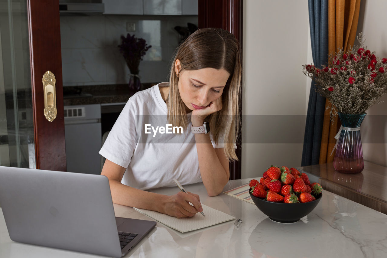 Woman using phone while sitting on table at home