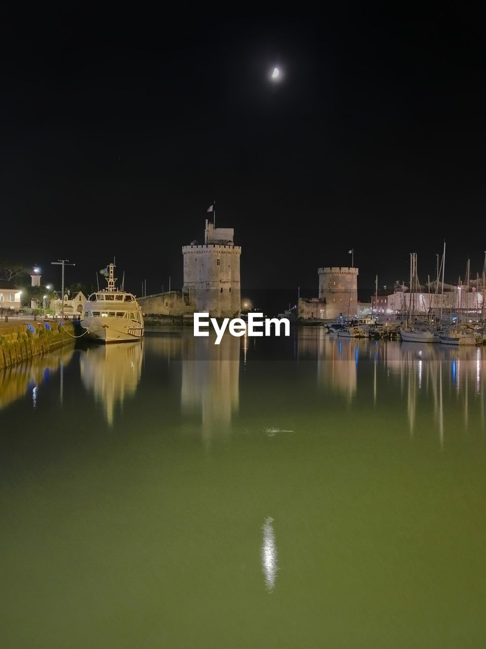 REFLECTION OF ILLUMINATED BUILDINGS IN SEA AT NIGHT