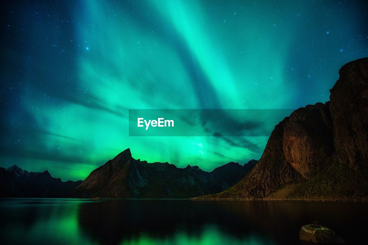 Scenic view of lake and mountains against aurora borealis at night