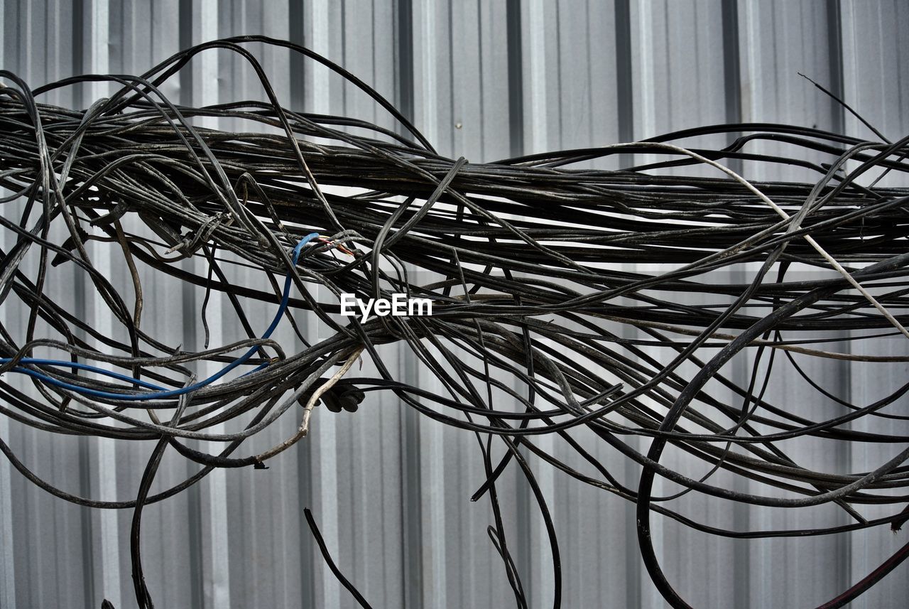 Close-up of tangled cables against corrugated wall