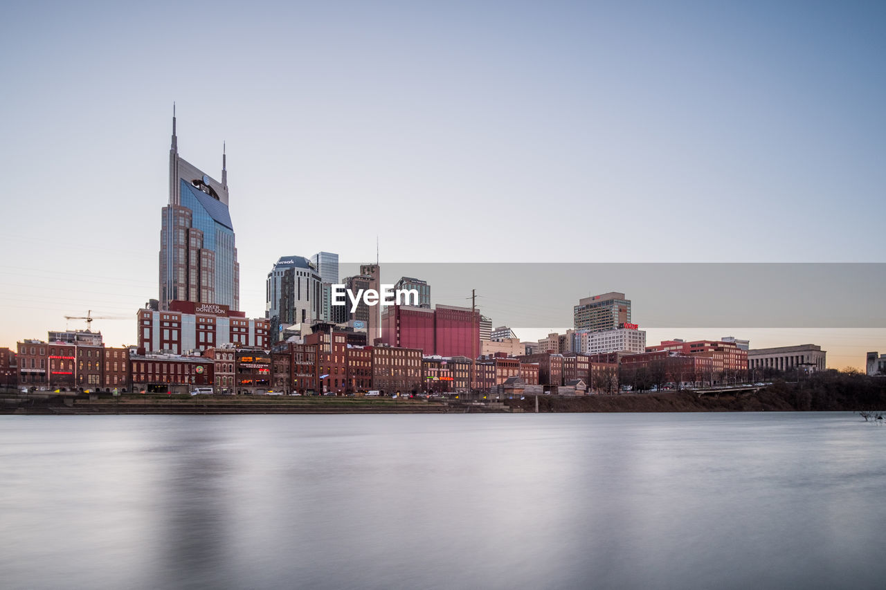 RIVER AMIDST BUILDINGS AGAINST CLEAR SKY