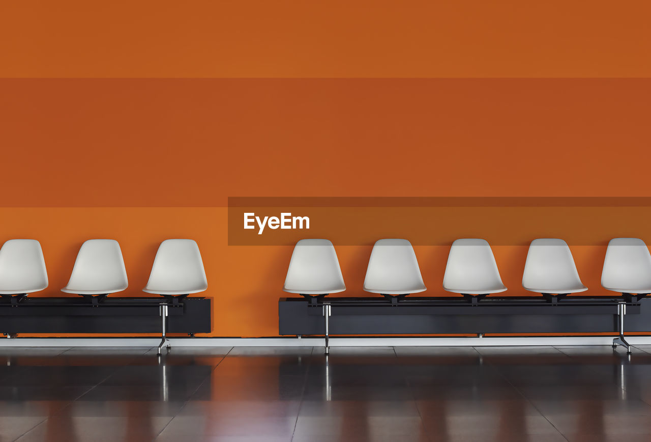 Empty chairs and table against orange wall