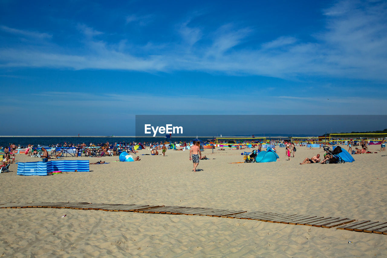 GROUP OF PEOPLE ON BEACH AGAINST SKY