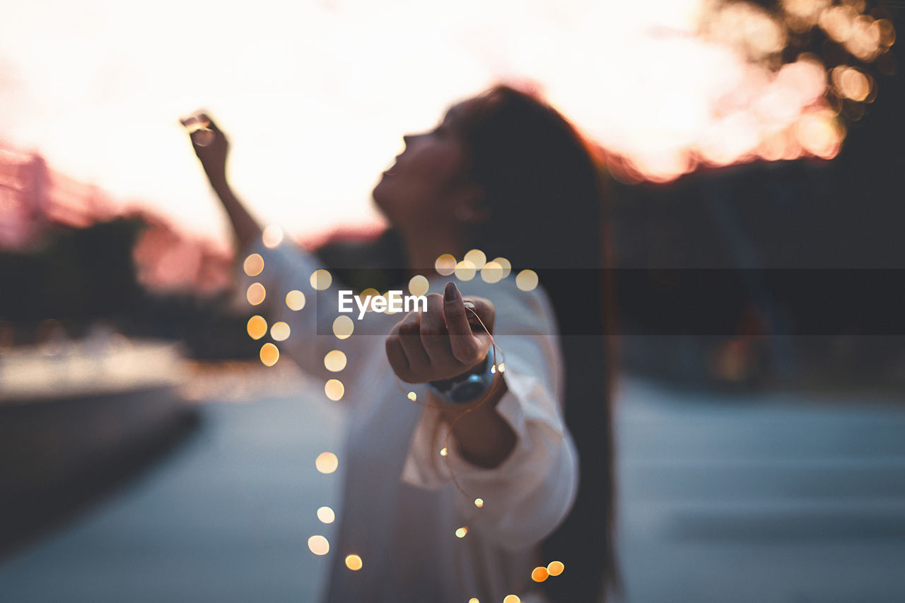 Close-up of hand holding illuminated lighting equipment at sunset