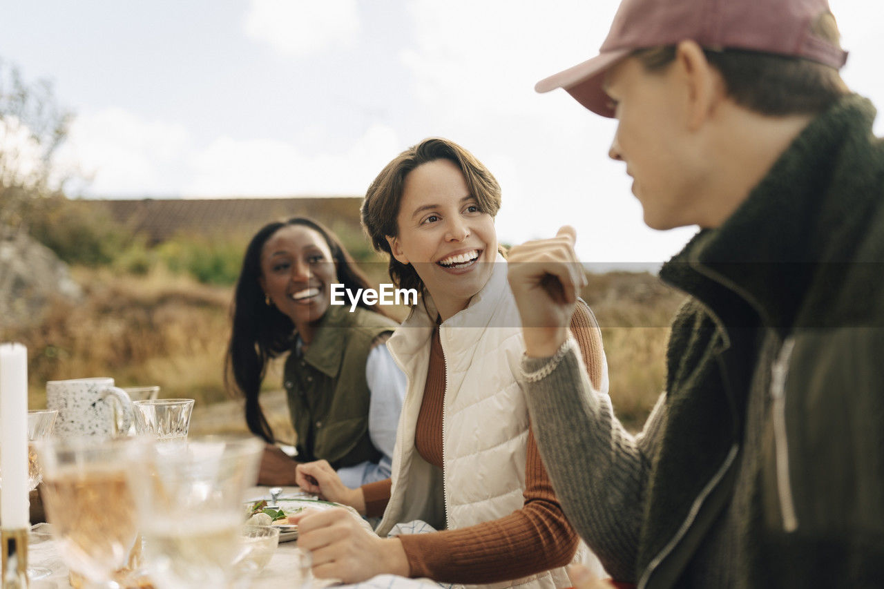 Happy woman talking with male friend at outdoor dinner party during social gathering