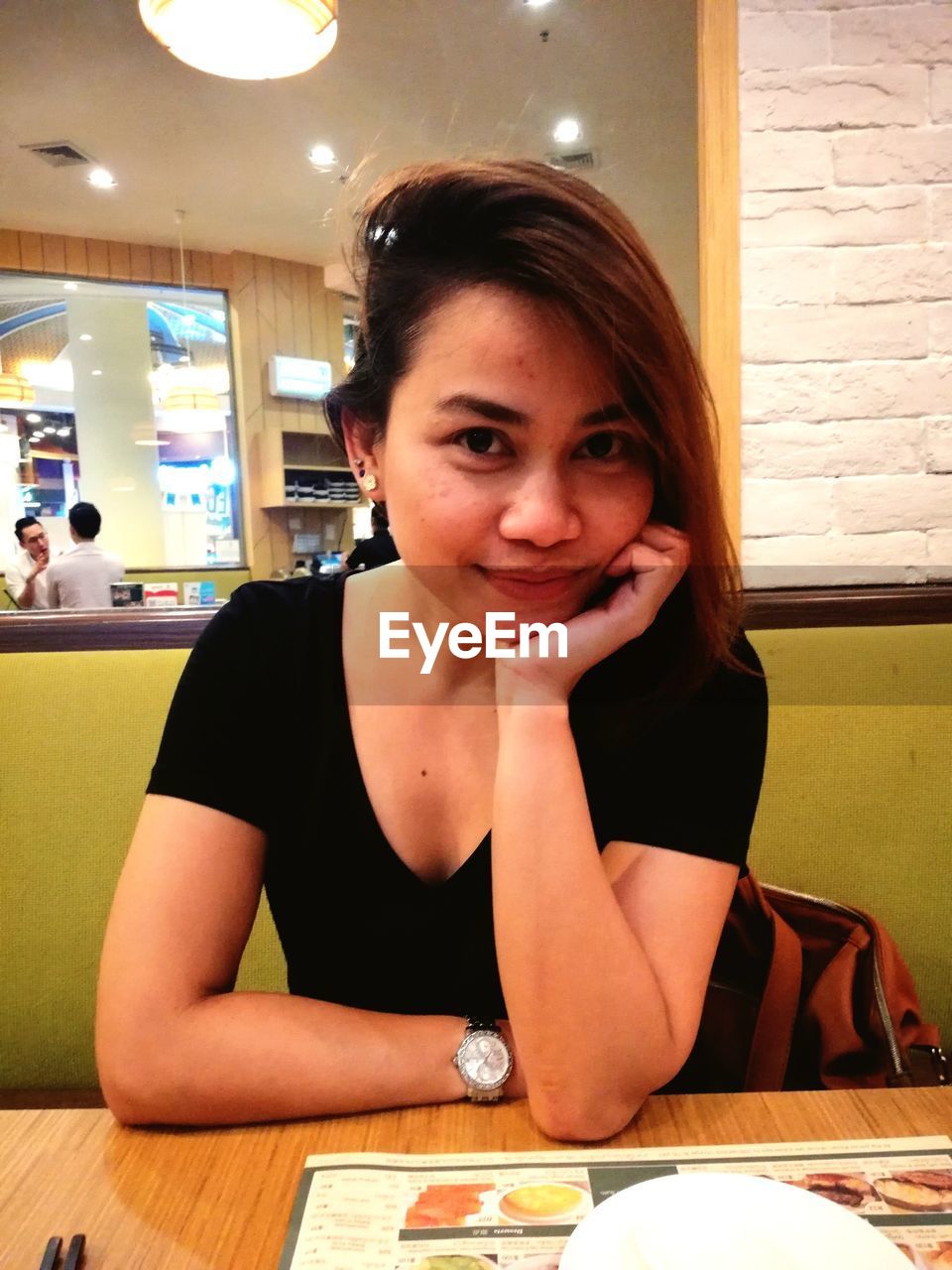 PORTRAIT OF A YOUNG WOMAN SITTING AT RESTAURANT