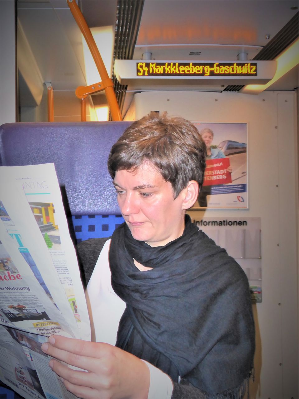 Woman reading newspaper while sitting in train