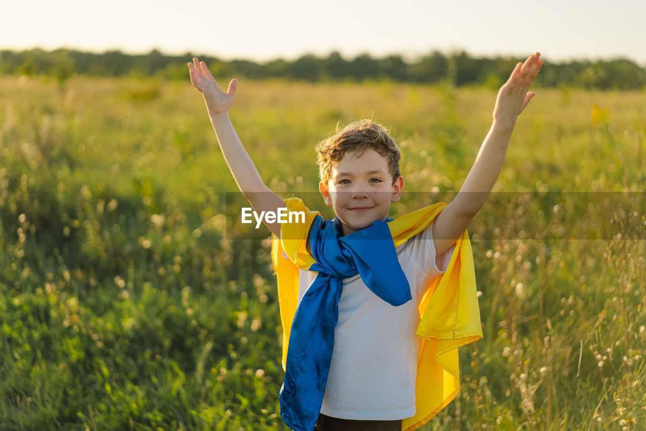 Ukrainian child boy in white t shirt with yellow and blue flag of ukraine in field.