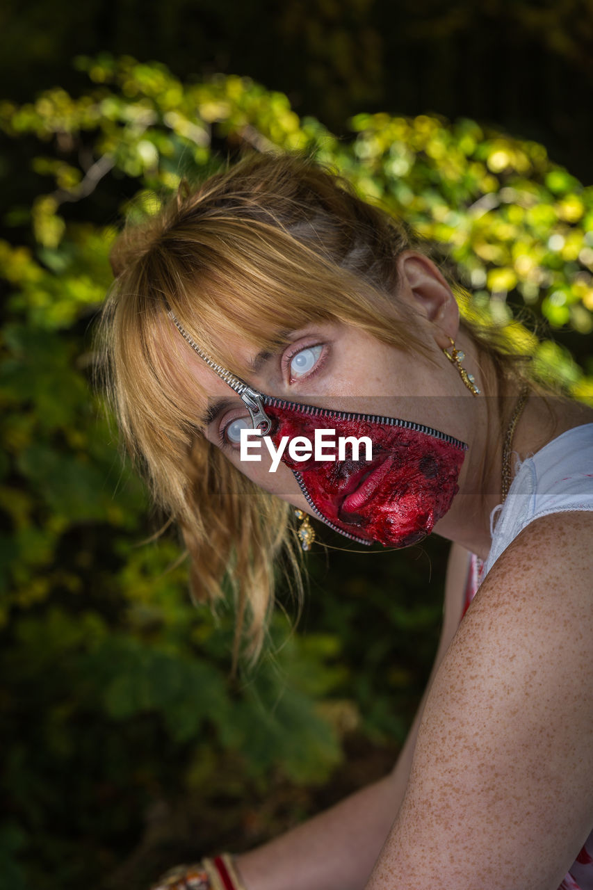 Woman with zipper and face paint against tree